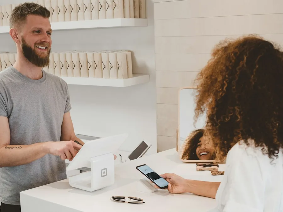 A guest at a cafe counter confirming a booking on their phone with a smiling barista