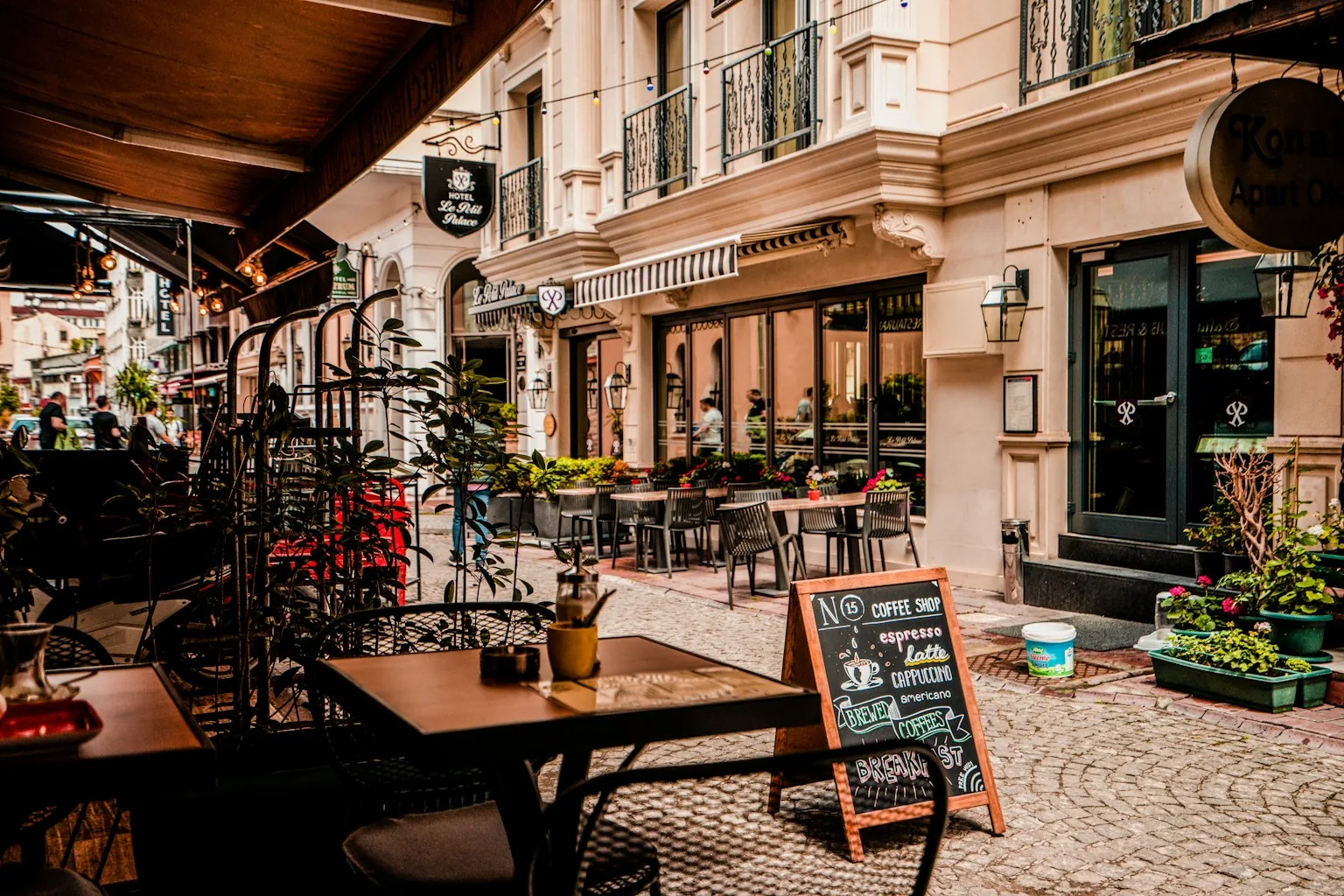 Outdoor cafe tables and chairs on a cobbled street outside a corner coffee shop